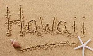 Hawaii written in the sand with a brown shell on the left and a white starfish on the right