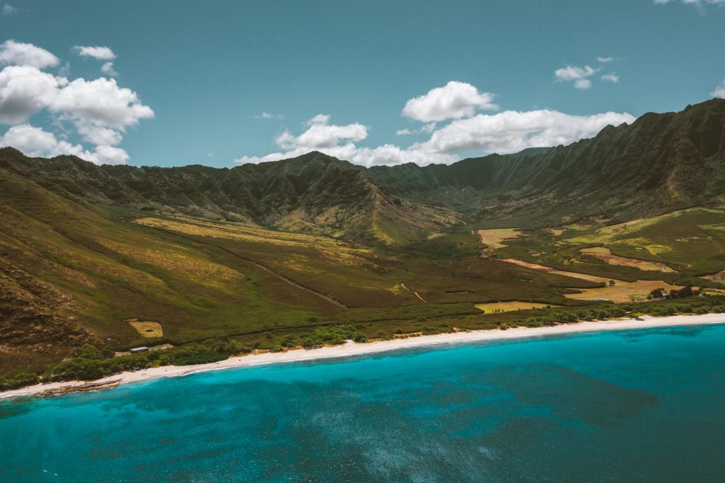A drone shot from the ocean, looking at the shoreline and mountains of Waianae