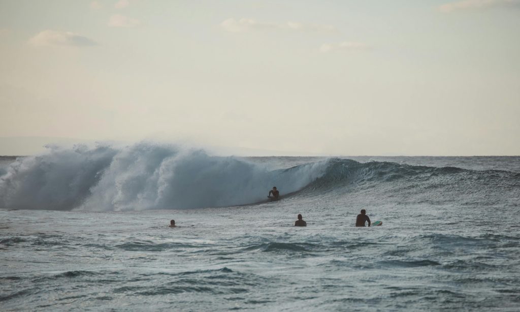 A group of surfers waiting in the ocean as a surfer is riding a wave